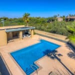 Sparkling blue community swimming pool at Casa Real Townhomes in Tucson, Arizona, surrounded by a tan sun deck and lush desert landscaping.