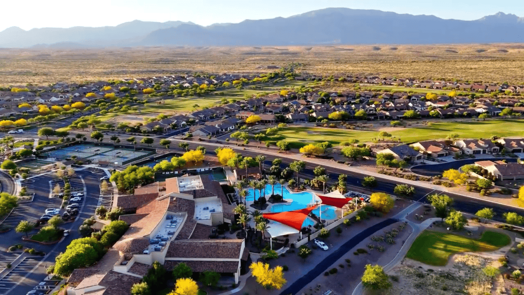 Aerial view of La Hacienda Club at SaddleBrooke Ranch with resort-style pool, tennis courts, golf course fairways, and the Catalina Mountains in the background.