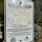 Hunting rules sign in Tucson Mountain Park showing archery hunting information and park regulations at a desert trail access point in Tucson, Arizona.